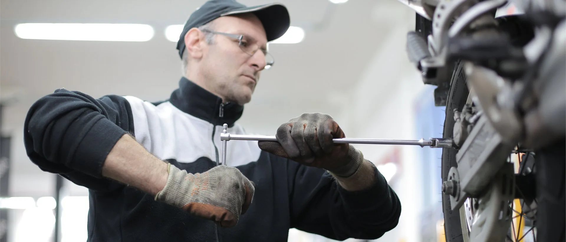 Mechanic using professional motorcycle repair tools in a workshop environment